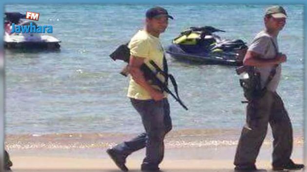 Photo montrant deux policiers en civil armés sur une plage : Une source policière met au point